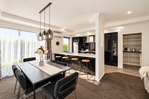 Une cuisine moderne dotée d’un îlot central, de tabourets de bar et de luminaires suspendus.