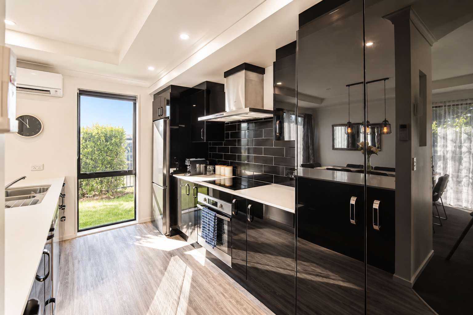 Een moderne keuken met een groot raam, roestvrijstalen apparatuur en uitzicht op de omgeving.