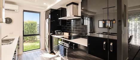 A modern kitchen with a large window, stainless steel appliances, and a view of the outdoors.