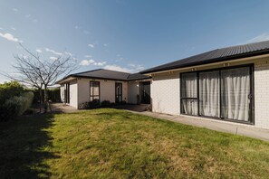 Ein modernes, zweistöckiges Haus mit gepflegtem Rasen, großen Schiebegläsern und einer Ziegel-Fassade.