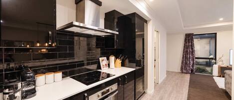 A modern kitchen with dark cabinetry, a stainless steel range hood, and a black countertop.