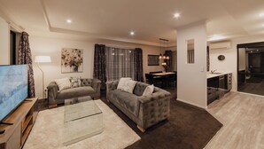 Una sala de estar moderna con un sofá gris, una mesa de centro de vidrio y un televisor de pantalla plana.