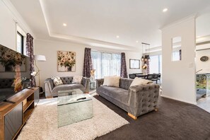 A modern living room with a grey sofa, a glass coffee table, and a wooden TV stand.