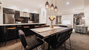 Una cocina moderna con una isla central, taburetes de bar e iluminación colgante.