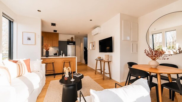 Una sala de estar moderna con un sofá, una mesa de centro y un comedor con mesa y sillas.