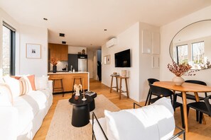 A modern living room with a sofa, a coffee table, and a dining area with a table and chairs.