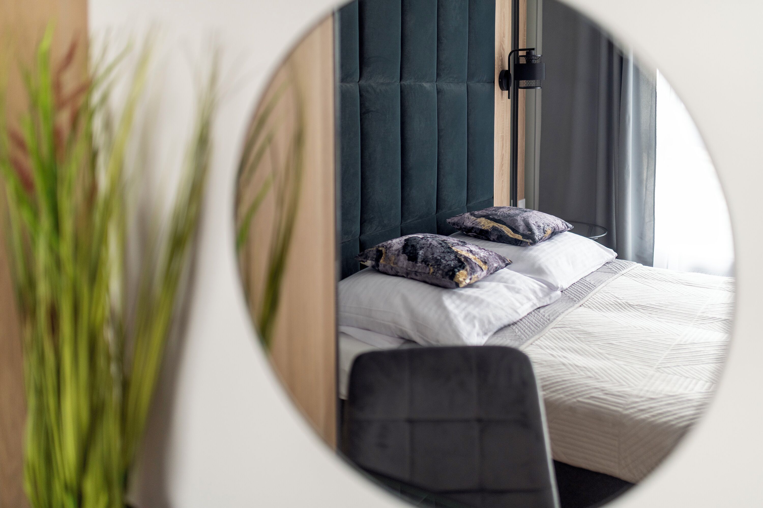 A bedroom with a bed, pillows, a chair, and a window.