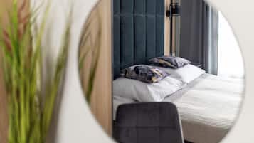 A bedroom with a bed, pillows, a chair, and a window.