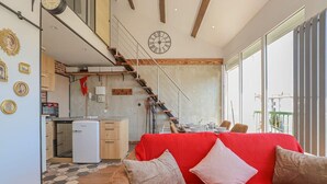 A modern interior with a red sofa, wooden staircase, kitchen, and large windows.