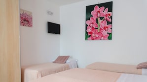Habitación de hotel con dos camas individuales, un televisor en la pared y un cuadro con motivos florales.