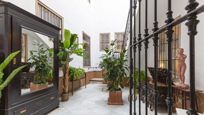 Um pátio amplo com um espelho grande, plantas em vasos e uma estátua.