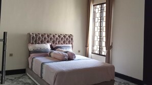 A bedroom with a bed, a ceiling fan, an air conditioning unit, a window with curtains, and a marble floor. - EXPRESS O 91708 Rumah Sriwijaya 12a Syariah (Jember)