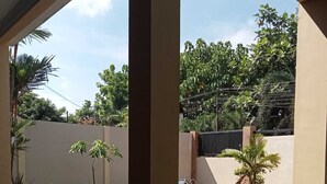 A covered patio area with a tiled floor, a low wall, and various plants. - EXPRESS O 91708 Rumah Sriwijaya 12a Syariah (Jember)
