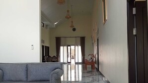 A spacious hallway with a marble floor, a grey sofa, and a wooden coffee table. - EXPRESS O 91708 Rumah Sriwijaya 12a Syariah (Jember)