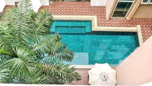 A swimming pool with a tiled border, surrounded by a brick patio and a palm tree. - 6-49 - 1 Bdr Condo with Balcony and shared Pool (Tambon Patong)
