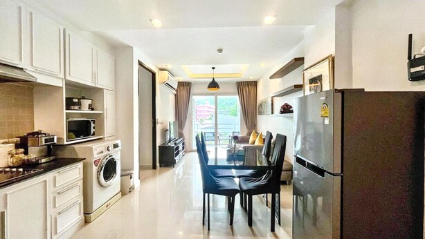 A modern kitchen with a washing machine, dining area with chairs, and a refrigerator. - 6-49 - 1 Bdr Condo with Balcony and shared Pool (Tambon Patong)