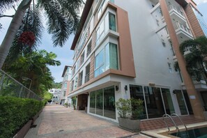 Un edificio moderno de varios pisos con fachada de vidrio, piscina y un jardín bien cuidado.