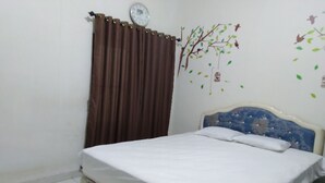 Une chambre à coucher avec un lit, un rideau, une horloge murale et un autocollant décoratif représentant un arbre.