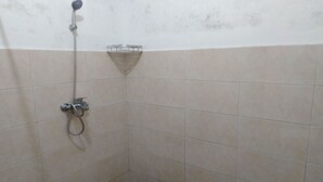 Un coin d’une salle de bain avec une douche, un porte-serviettes et un pommeau de douche.