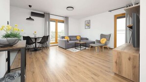 A modern living room with a sofa, coffee table, and dining area. - Modern Apartment | Private Parking and Balcony (Konstancin-Jeziorna)