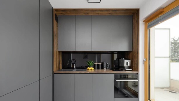 A modern kitchen with grey cabinets, a wooden countertop, and a built-in oven. - Modern Apartment | Private Parking and Balcony (Konstancin-Jeziorna)