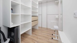 A modern, white interior with built-in shelving, a bench, and a vacuum cleaner. - Charming Apartment near Warsaw | Parking, Air Conditioning (Konstancin-Jeziorna)