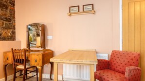 A room with a wooden desk, a chair, a red patterned sofa, a mirror, and two framed certificates on the wall. - The Red Admiral Hotel (Seascale)