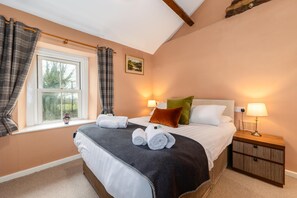 A bedroom with a large bed, two bedside lamps, a window with curtains, a nightstand, and a painting on the wall. - The Red Admiral Hotel (Seascale)
