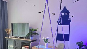 A modern living room with a hanging chair, a dining table, and a TV.