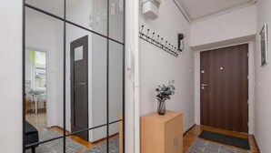 Ein Flur mit einem Spiegel, einem Holzschrank, einer Tür und einer kleinen Pflanze.