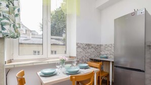 Eine kompakte Küche mit Esstisch für vier Personen, einem Kühlschrank und einem Fenster mit Vorhängen.