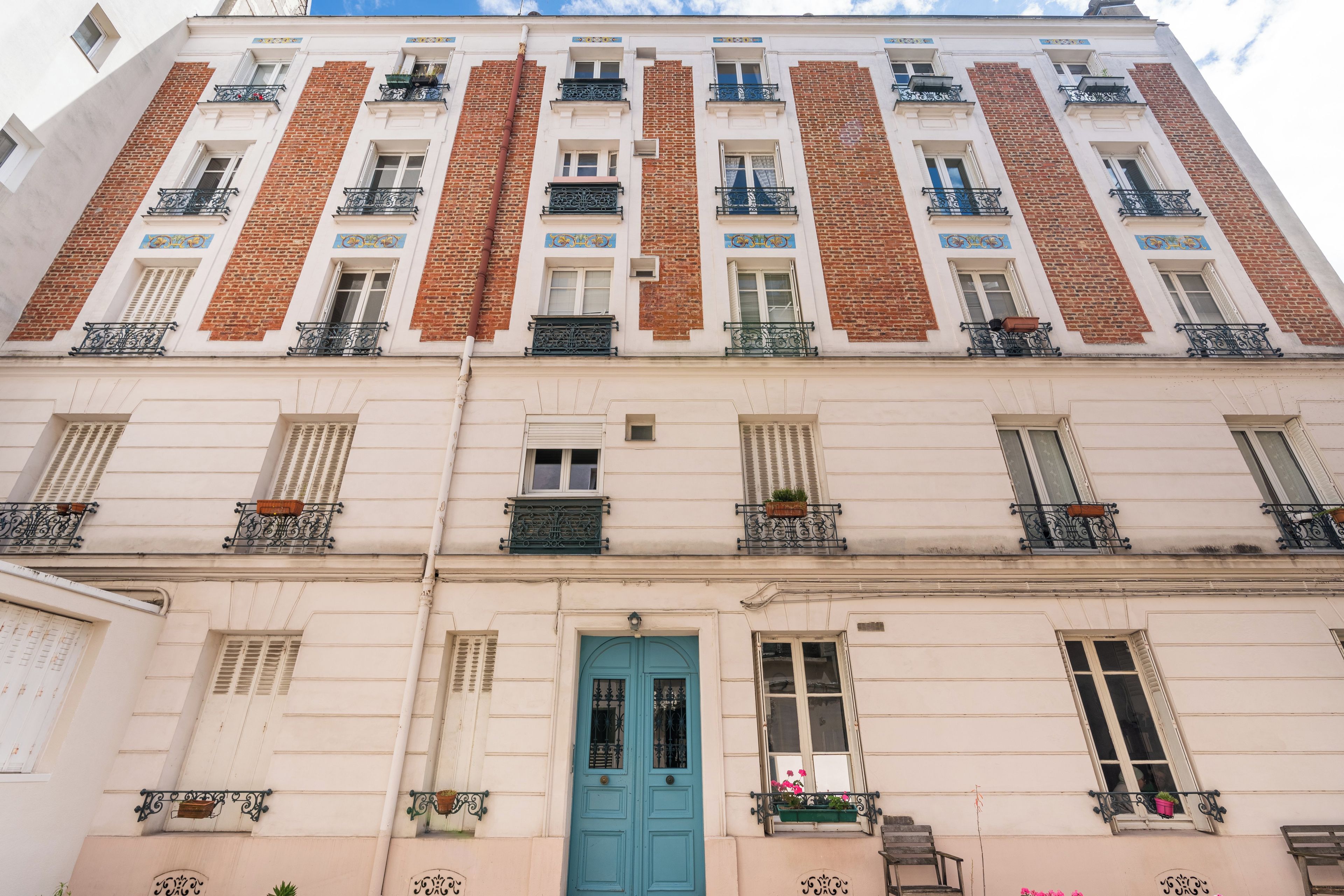 A multi-story building with a central entrance, balconies with wrought iron railings, and a mix of brick and plaster facades.