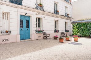 A building with a blue door, potted plants, and a tiled courtyard.