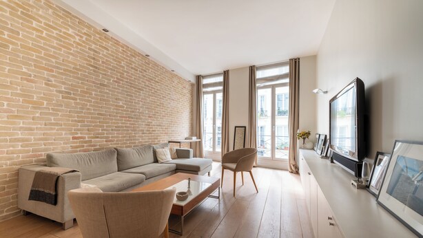 Un salon moderne avec un mur en briques, un canapé, une table basse et un téléviseur fixé au mur.