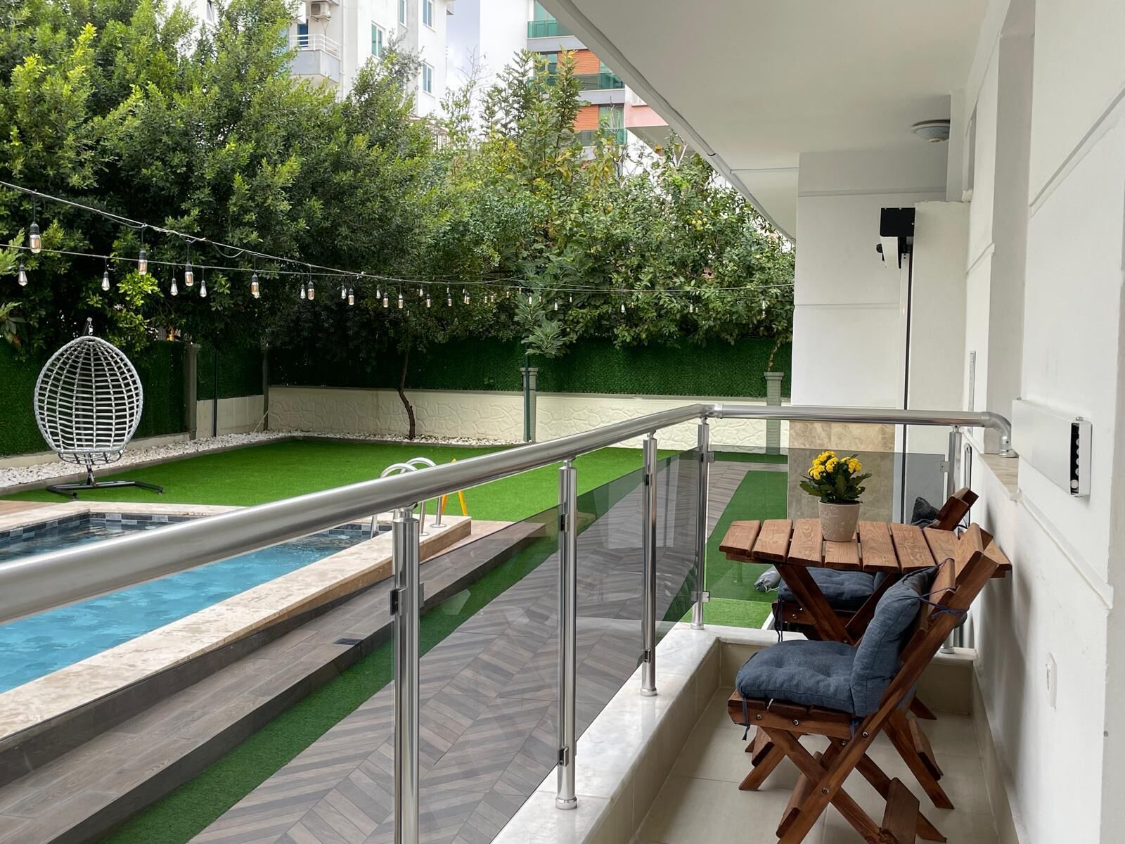 Un balcón con piscina, mobiliario exterior e iluminación colgante.
