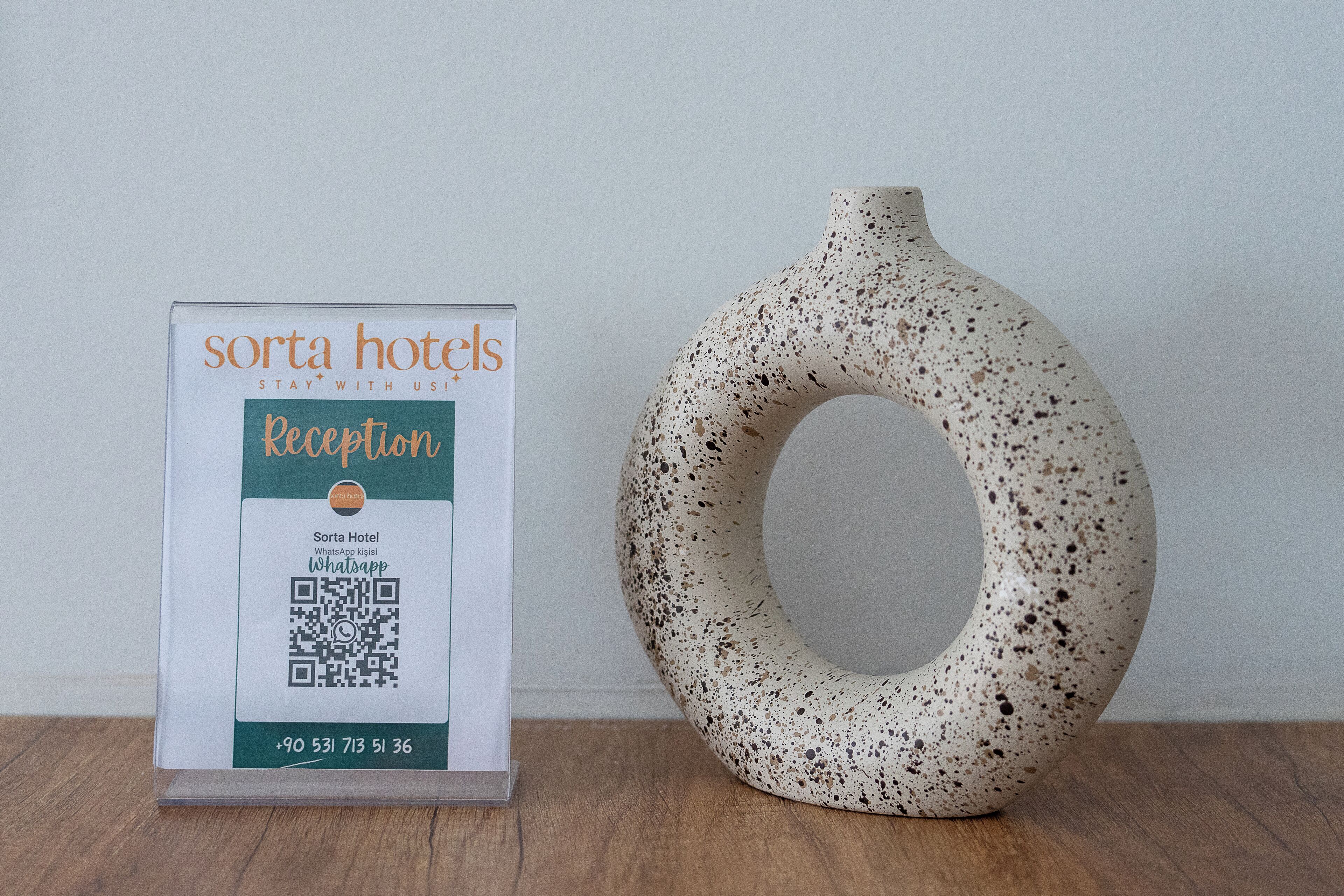 Señal de recepción para Sorta Hotels con un código QR y número de contacto.