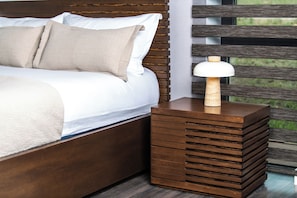 A neatly made bed with a wooden headboard and a bedside table with a lamp.