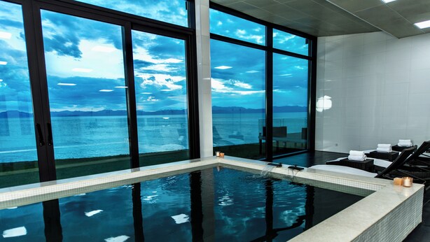 Une piscine intérieure avec vue sur la mer, grâce à de grandes baies vitrées.