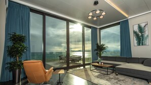 Un salon moderne doté d’une grande porte vitrée donnant sur un balcon qui offre une vue sur une étendue d’eau.
