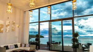 Un salon moderne doté d’une grande porte vitrée donnant sur un balcon qui offre une vue sur un plan d’eau.