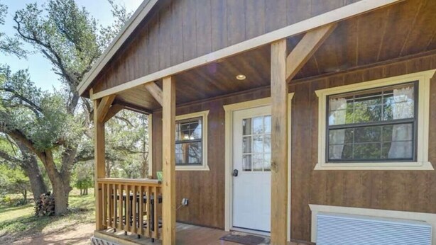 Une cabane en bois avec une véranda, une porte et des fenêtres.