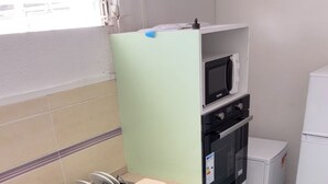 Una cocina con un lavamanos, un microondas, un horno y un refrigerador.