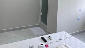 Una habitación de hotel moderna con una televisión de pantalla plana montada en la pared, un aire acondicionado instalado en el techo y una lámpara colgante.