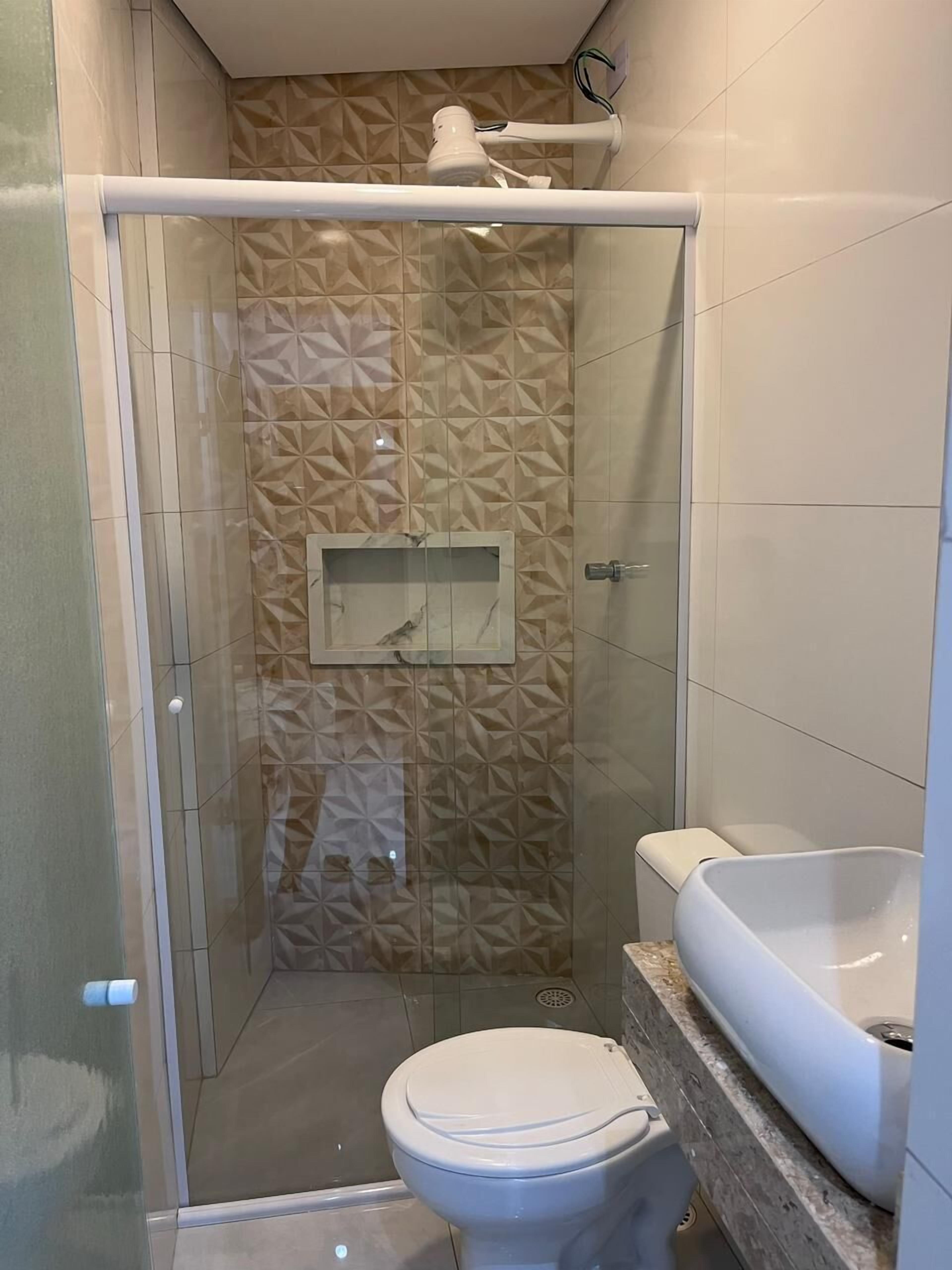 A bathroom with a glass-enclosed shower, a toilet, and a sink.
