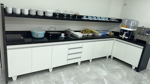 Una cocina moderna con armarios blancos, encimera negra y una zona de café con dispensador de agua.