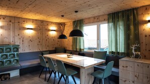 A wooden cabin interior with a dining table, chairs, a bench, and a cabinet.