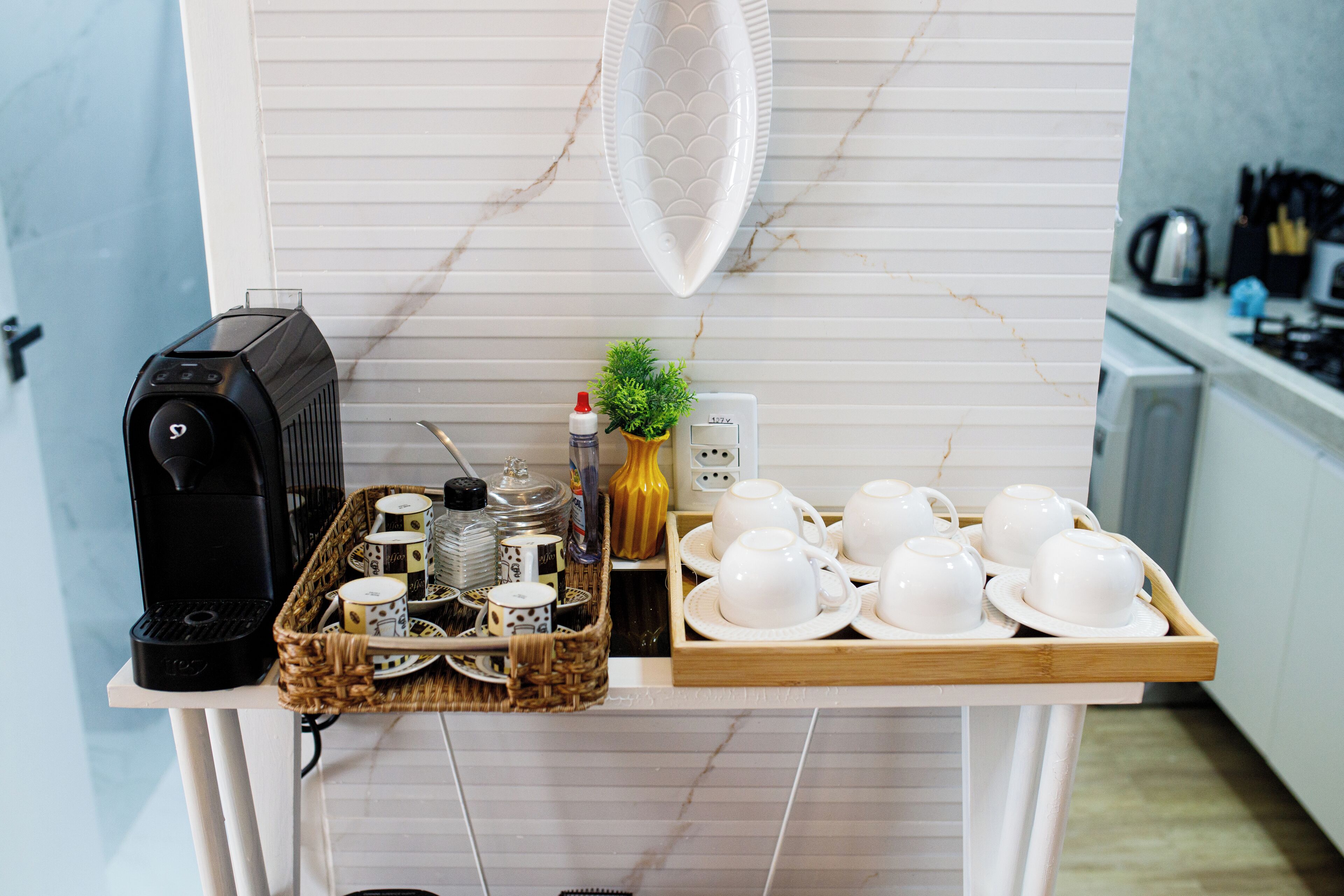 A kitchen counter with a coffee maker, tea set, and various kitchen utensils.