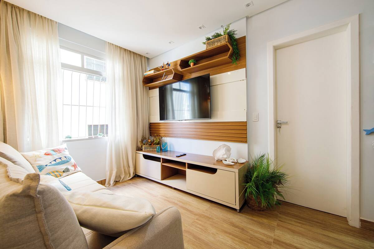 A modern living room with a flat-screen TV, wooden shelves, and a comfortable sofa.