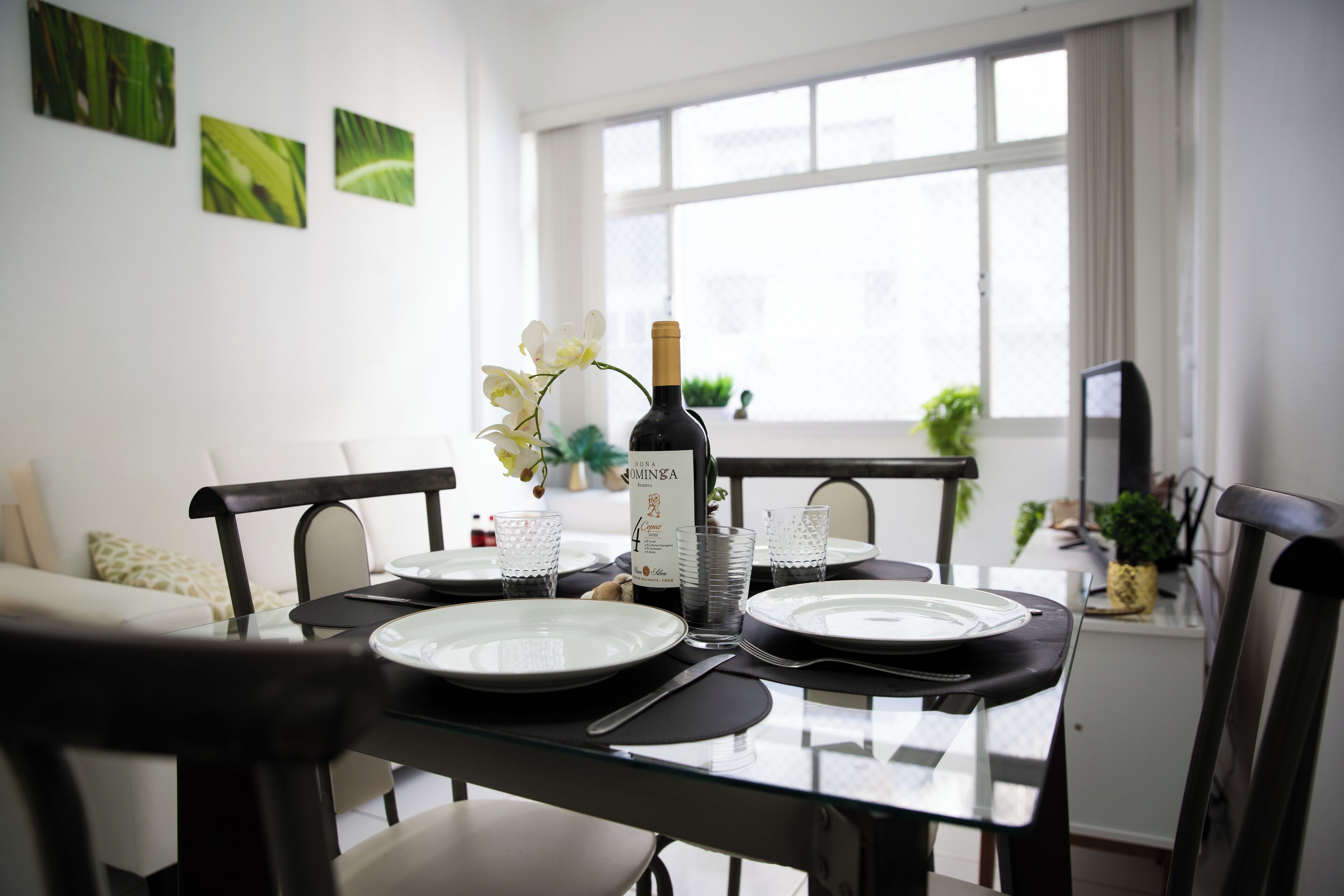 A dining table set with plates, glasses, and a bottle of wine.