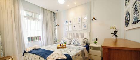 A bedroom with a bed, bedside tables, a desk, and a window with curtains.